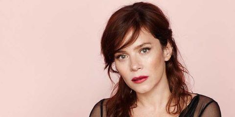 actress anna friel with wither brunette hair pulled up in the back and a serious look on her face while she wears a mesh black shirt